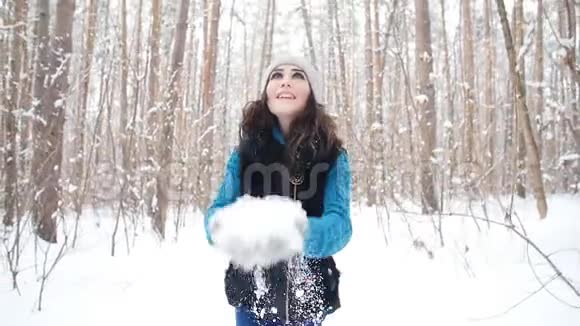 在冬天的森林里一个年轻的女人微笑着把雪抛起视频的预览图