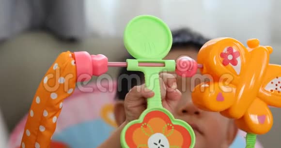 可爱的小男孩用手指在头顶上玩五颜六色的玩具视频的预览图