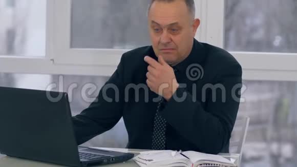 商务人员退休人员使用笔记本电脑工作并在办公室笔记本上做笔记视频的预览图