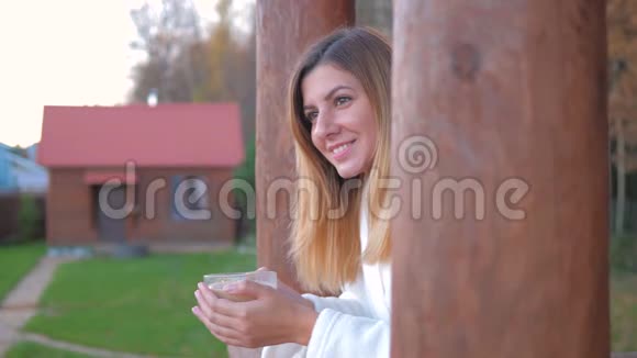 穿着浴袍的女人喝着热咖啡卡布奇诺在阳台上从原木上消失视频的预览图