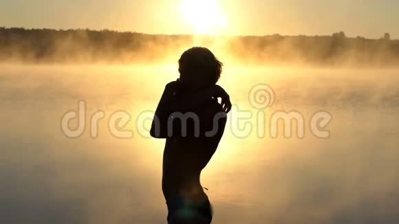 日落时分年轻人在湖畔挥动手臂视频的预览图