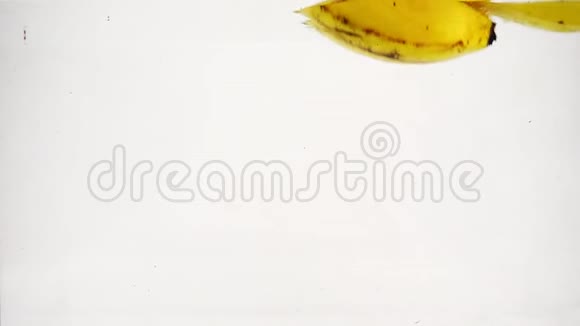 香蕉掉进水里有很多小气泡香蕉在孤立的白色背景上的视频视频的预览图