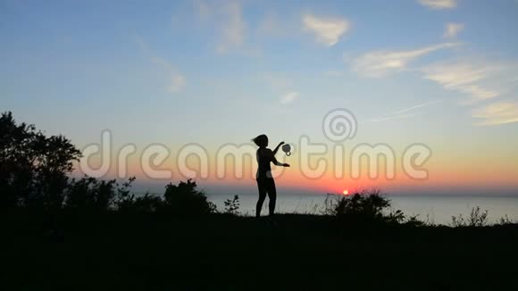 美丽女人用水壶铃在夕阳下锻炼的剪影视频的预览图