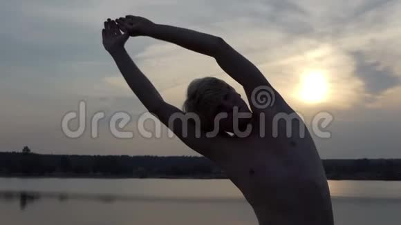年轻人举起双手在太阳落山时弯下腰视频的预览图