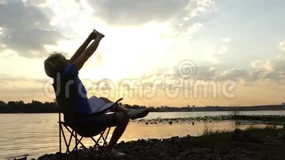 一个活泼的人坐在河堤上在夕阳下做运动视频的预览图