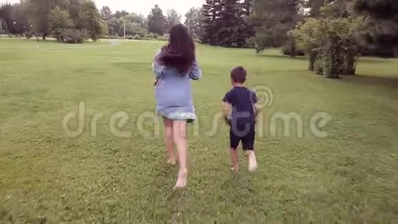 一个小男孩带着一个女孩跑在草地上笑着跳着心情很好视频的预览图