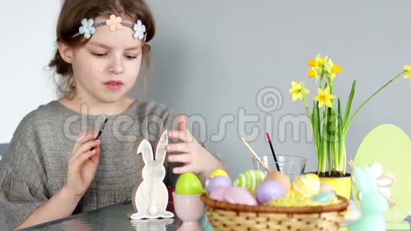 一个可爱的女孩准备复活节画复活节兔子桌子上有一个复活节篮子视频的预览图