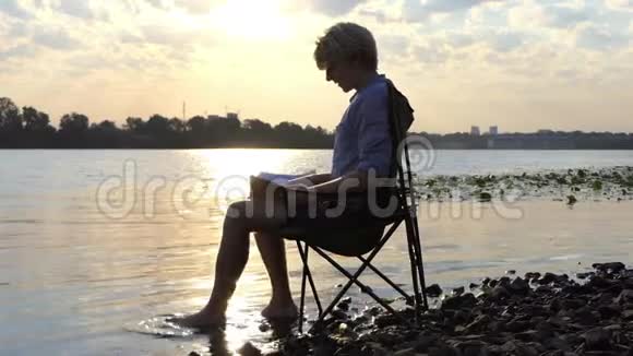 在斯隆莫的河岸上年轻人在水中啜泣微笑和移动他的赤脚视频的预览图
