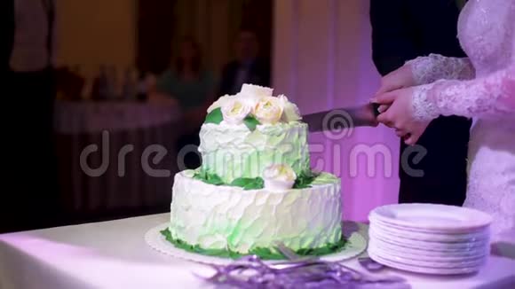 新娘切婚礼蛋糕新娘和新郎正在切婚礼蛋糕新郎新娘的手切一片视频的预览图