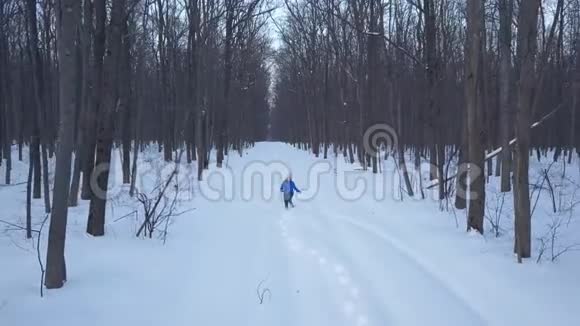 在森林里的雪堆里跑来跑去的快乐女孩的鸟瞰图冬季景观视频的预览图