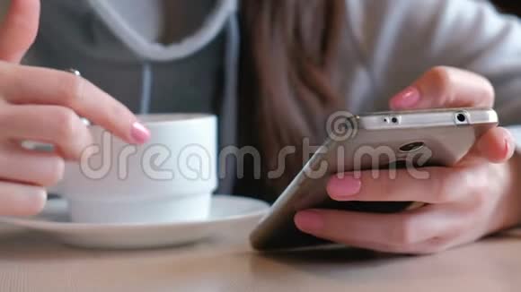 女人正在用勺子喝热巧克力看着坐在咖啡馆里的手机屏幕特写女郎视频的预览图