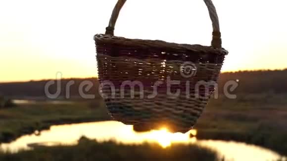 夕阳西下女性手在湖岸旋转一个民间篮子视频的预览图