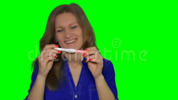 微笑的女人拿着积极的怀孕测试把它展示给镜头视频的预览图