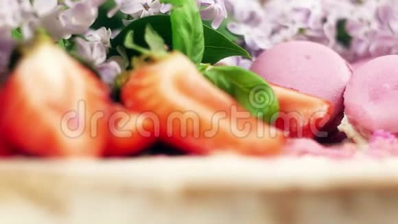用马卡龙草莓片和紫丁香的花4K慢潮将旋转蛋糕装饰得紧密视频的预览图