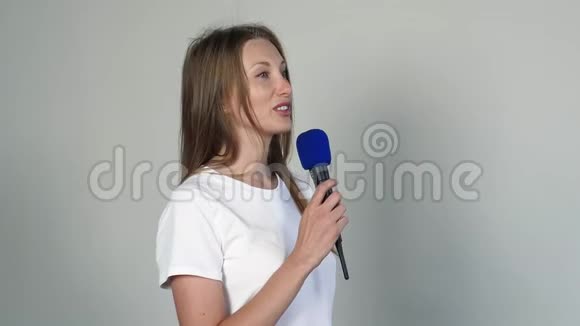 年轻漂亮的女人用麦克风说话视频的预览图
