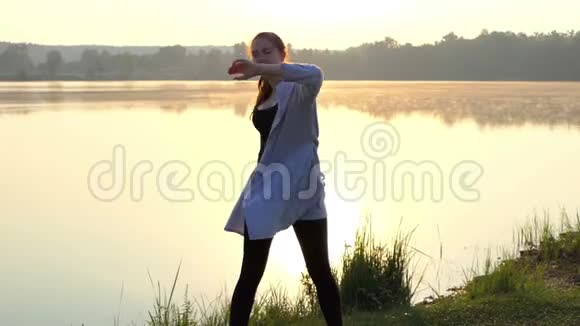 一个怀孕的女人站在垫子上把她的手臂放在一边在斯隆莫的日落视频的预览图