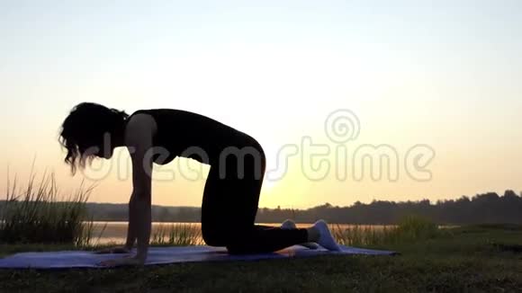 一个女人站在垫子上四个人在日落时抬起她的腿视频的预览图