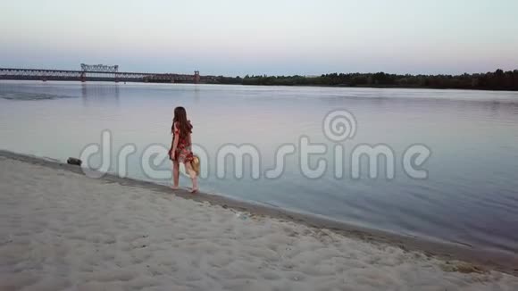 迷人的年轻女子正走在河岸的沙滩上视频的预览图