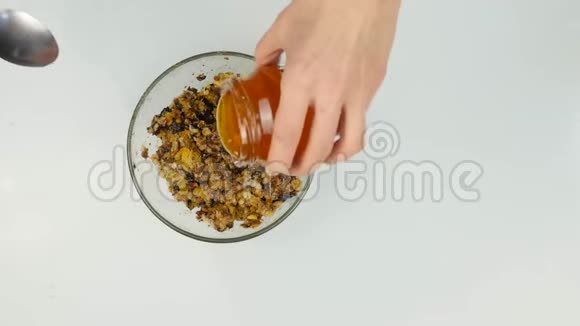 女人在坚果黄油中加入蜂蜜然后把配料混合在碗里4K视频的预览图
