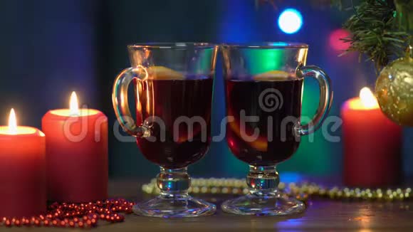 一棵圣诞树模糊的背景上摆着两杯覆盖的葡萄酒五颜六色的圣诞灯和红烛视频的预览图