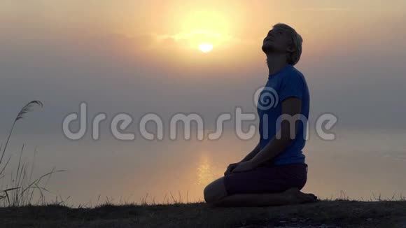 夕阳西下年轻人弯着腿坐在湖岸上视频的预览图