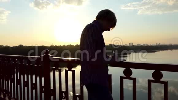 才华横溢的人站着把他的想法写在夕阳西下的一座桥上视频的预览图
