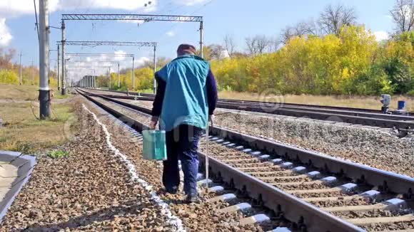 手杖和绿色手提箱在铁路旁行走的人视频的预览图