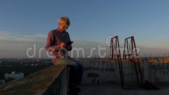 日落时分盖伊坐在高处的建筑工地上看着他的手机视频的预览图