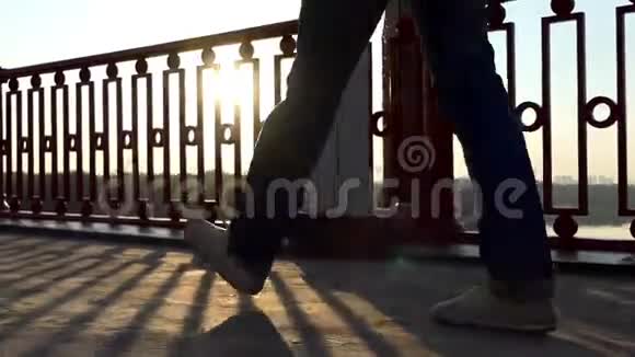 一个年轻人的腿在邋遢的桥上闪耀着灿烂的夕阳视频的预览图