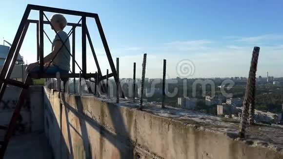 金发碧眼的男人坐在莲花的阿萨纳上坐在一座建筑的金属梯子上视频的预览图