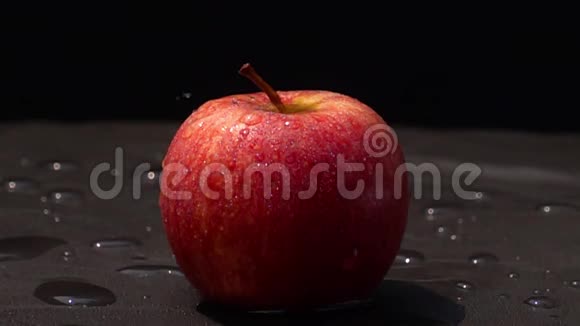 把新鲜水洒在黑底红苹果上视频的预览图