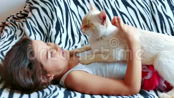 小女孩抱着一只猫躺在床上女孩和宠物白猫的友谊关心爱情女孩和猫的生活方式视频的预览图