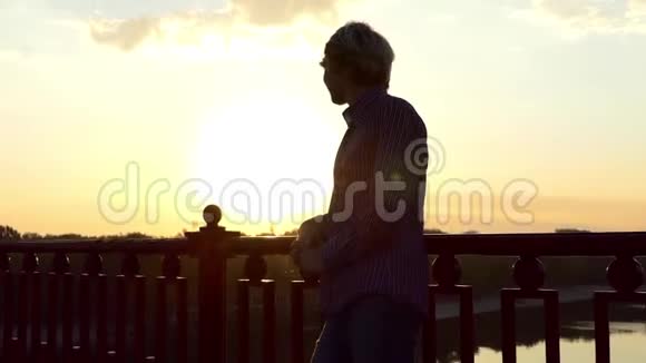 年轻的金发男子在迪尼普罗河大桥上享受灿烂的日落视频的预览图