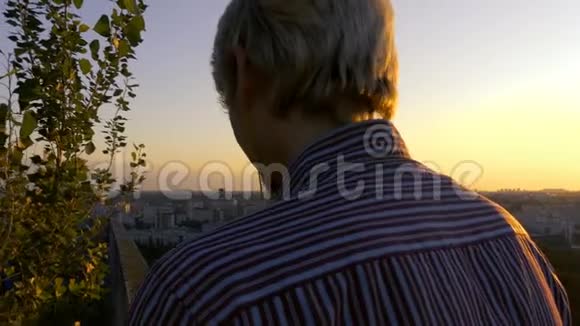 4K微笑的男人带着耳机在日落时播放音乐视频的预览图