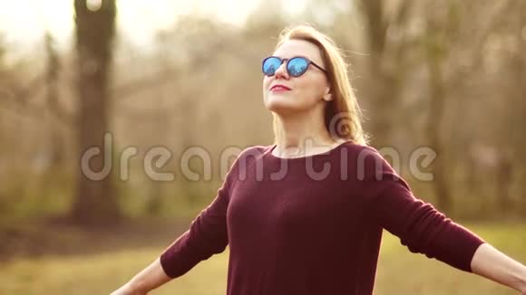 一个戴眼镜的30岁漂亮女人把脸对着春天的太阳他整理双手朝着视频的预览图