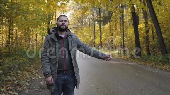 秋天站在高速公路上的年轻人搭便车冒险和旅游概念视频的预览图