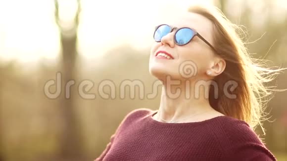一个戴眼镜的30岁漂亮女人把脸对着春天的太阳他整理双手朝着视频的预览图