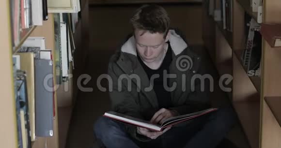 坐在图书馆地板上看书的男学生视频的预览图