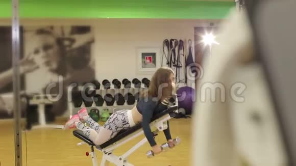 那个女孩用哑铃在健身房训练力量训练女性健身视频的预览图