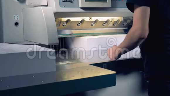一名员工正在一台切割机下调整两大堆纸张将它们分成四部分犁出视频的预览图
