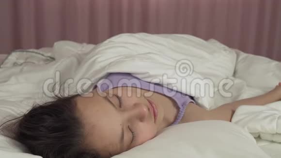 美丽的少女在床上醒来微笑着观看录像视频的预览图
