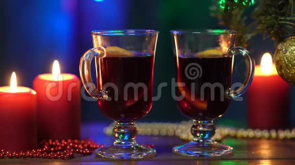 一棵圣诞树模糊的背景上摆着两杯覆盖的葡萄酒五颜六色的圣诞灯和红烛视频的预览图