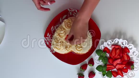 一个女人正在用草莓装饰一块涂满奶油的饼干碟子旁边是一个切片草莓视频的预览图