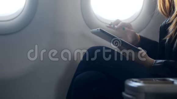 女士手里拿着现代平板电脑坐在飞机上视频的预览图