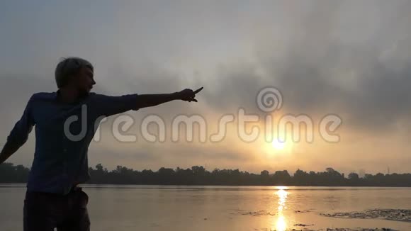 在斯隆莫的夕阳下年轻人两只手在河岸边转过身视频的预览图