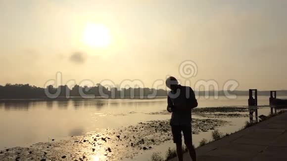 大胡子男站着看着他的智能手机在日落的斯隆莫视频的预览图