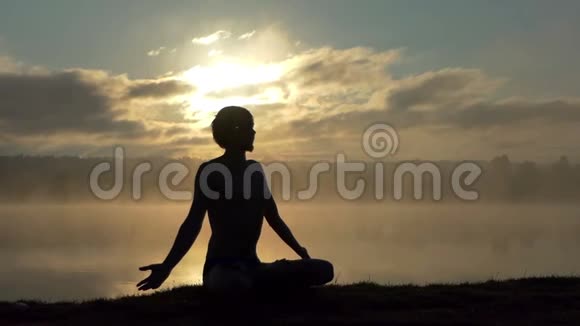 年轻人坐在湖岸上慢慢地在日落时做一个爱的标志视频的预览图