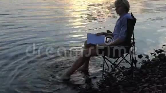 有才华的人在河岸边的水中啜泣微笑和移动他的赤脚视频的预览图
