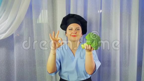 一个穿着围裙做饭的女人微笑着手里拿着西兰花露出她的手好吗视频的预览图