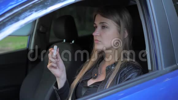 性感的金发女人坐在车里用口红视频的预览图